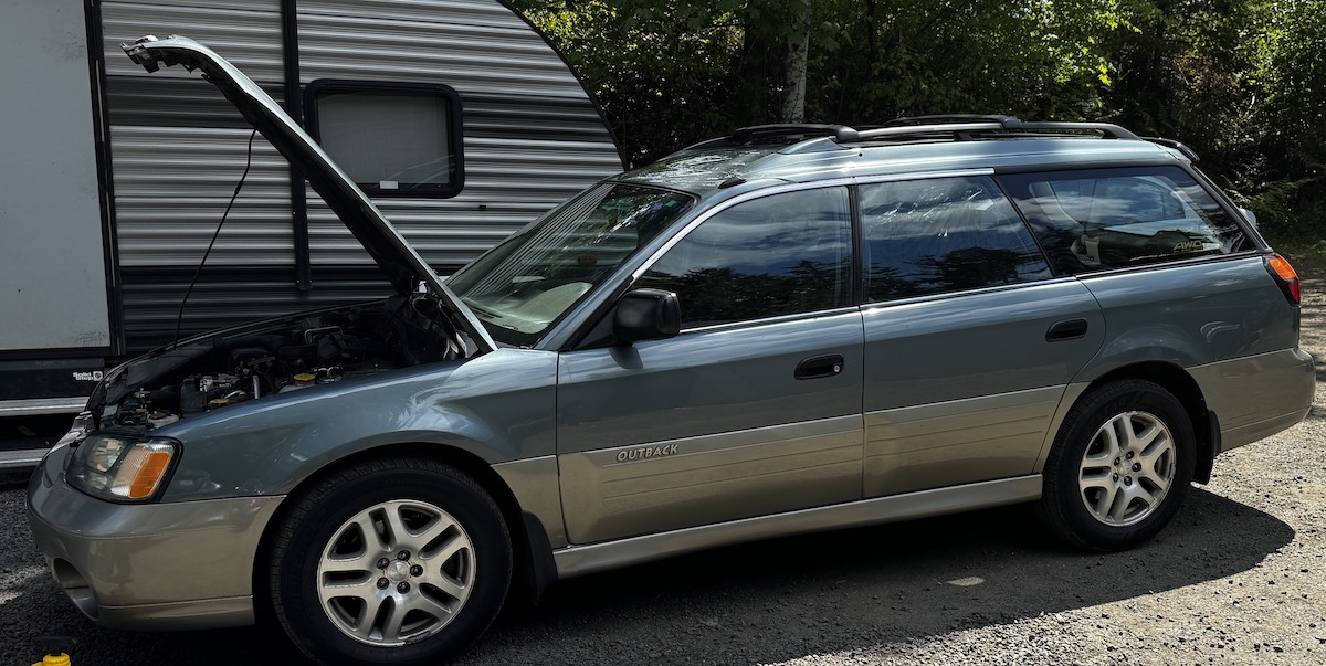 A 2001 Subaru Outback with its hood open for repairs.
