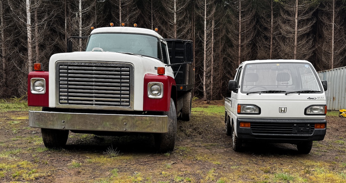 An International Loadstar dump truck parked next to a Honda Acty kei truck.