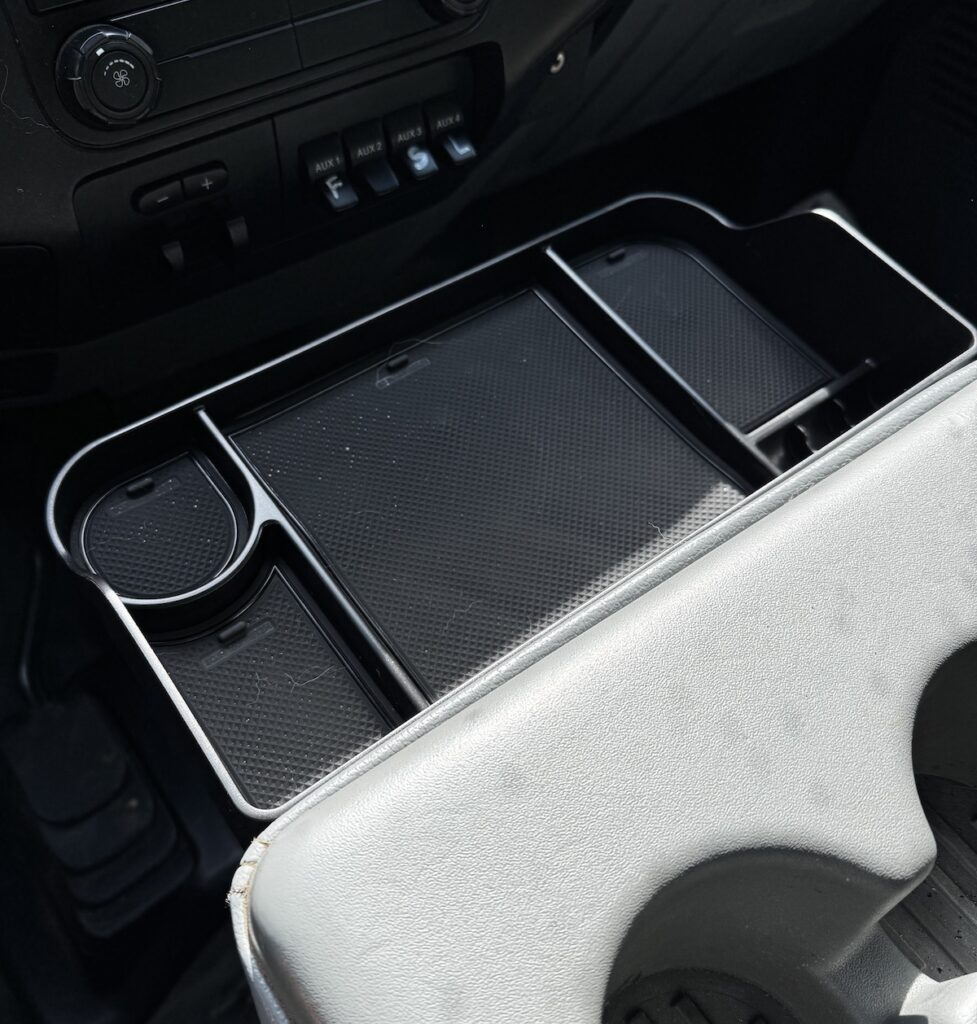 An aftermarket center console tray for a Ford F250.